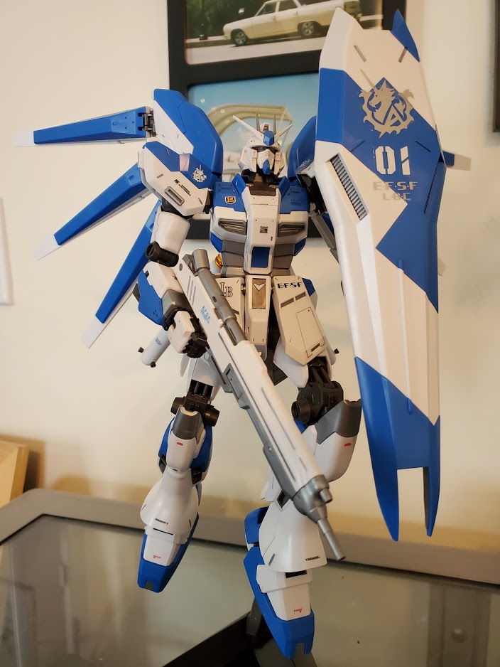 Photo of an MG Hi-Nu Gundam model kit. It is posed holding its shield up and holding a gun.
