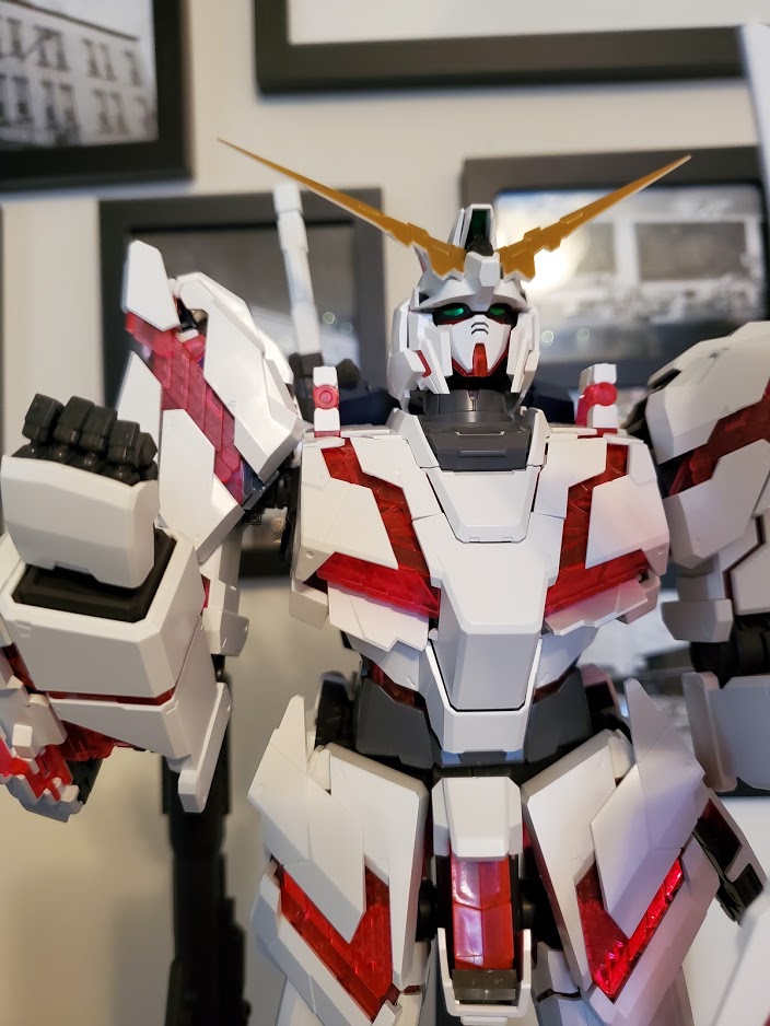 Photo of a PG RX-0 Unicorn Gundam. It is posed in Destroy Mode with a curled fist held upwards.